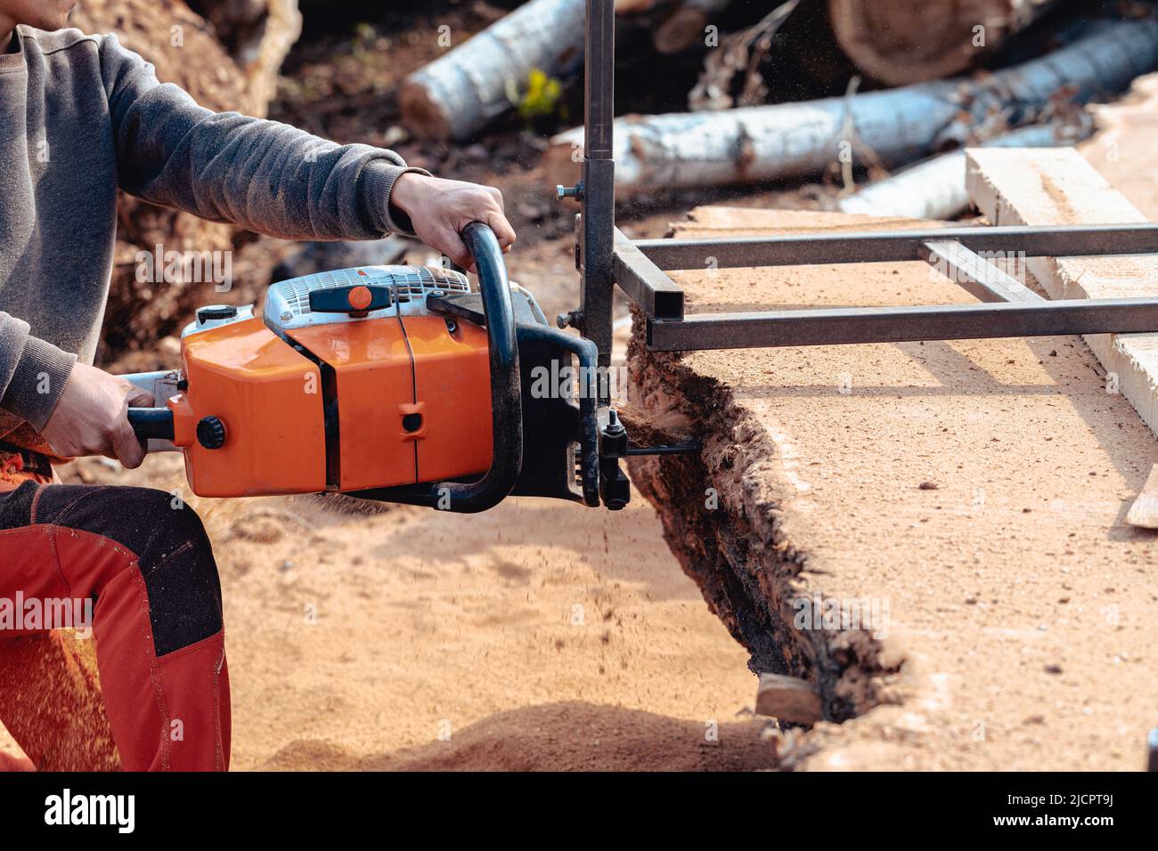 Nahaufnahme eines Holzfällers, der Baumstamm mit einer riesigen Kettensäge schneidet, um Holzbretter zu machen Stockfoto