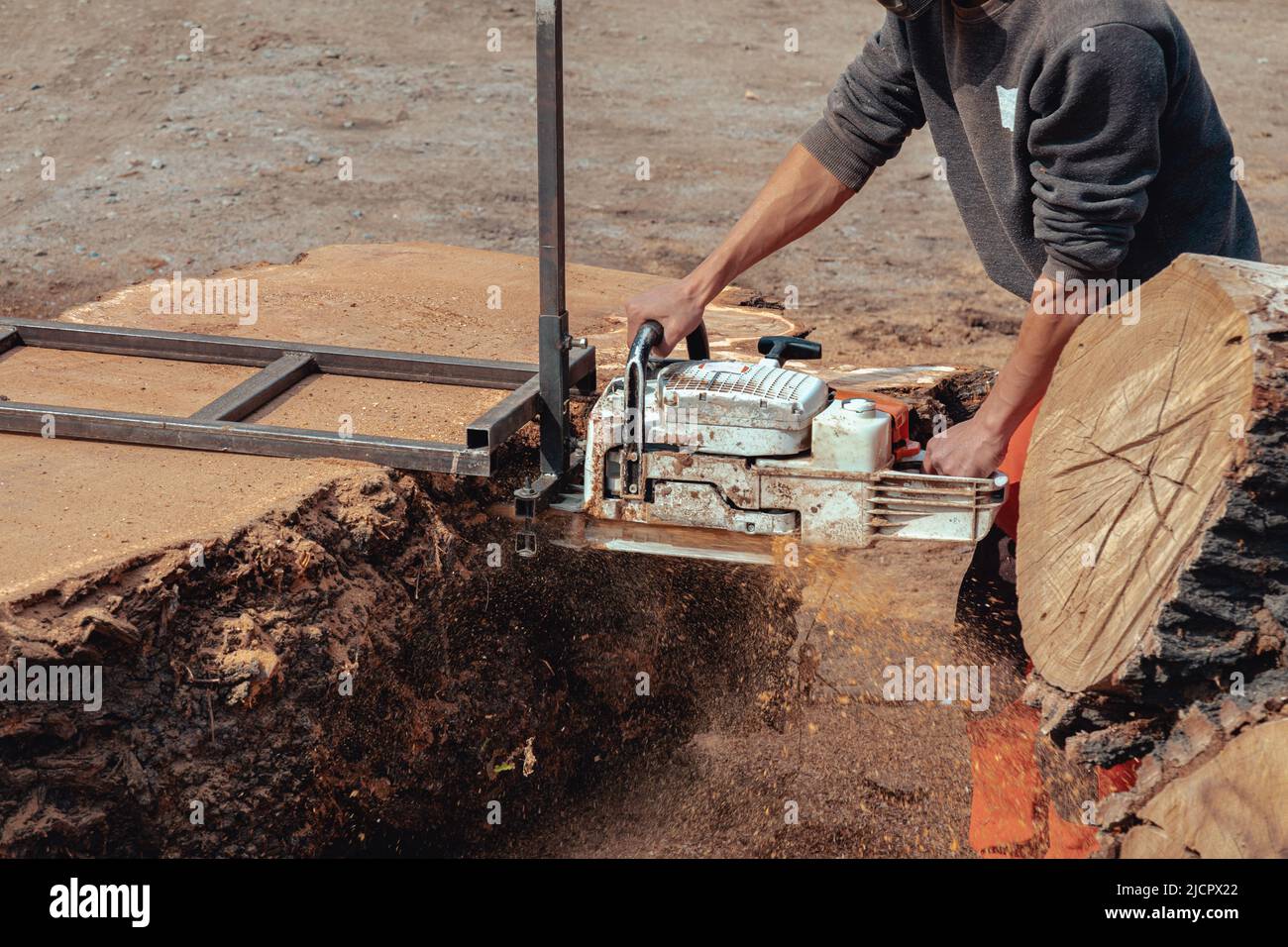 Nahaufnahme eines Holzfällers, der Baumstamm mit einer riesigen Kettensäge schneidet, um Holzbretter zu machen Stockfoto