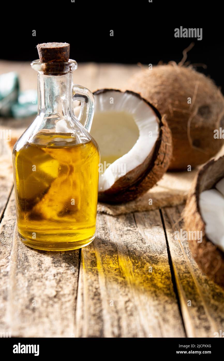 Kokosöl und Ölflasche auf Holztisch Stockfoto
