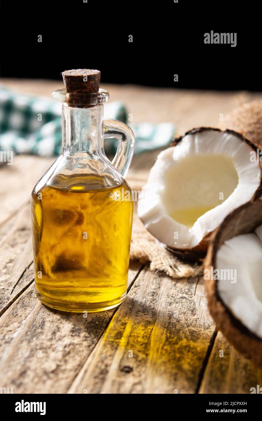 Kokosöl und Ölflasche auf Holztisch Stockfoto