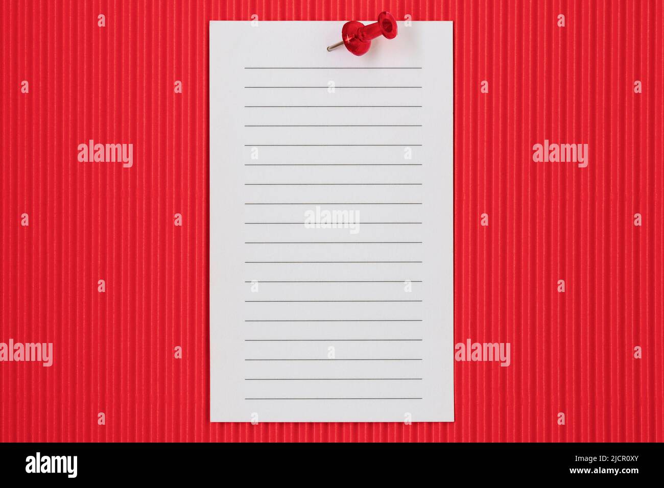 Weißes liniertes Papier, das auf rotem Hintergrund für Notizen, Mitteilungen oder To-Do-Listen fixiert ist Stockfoto