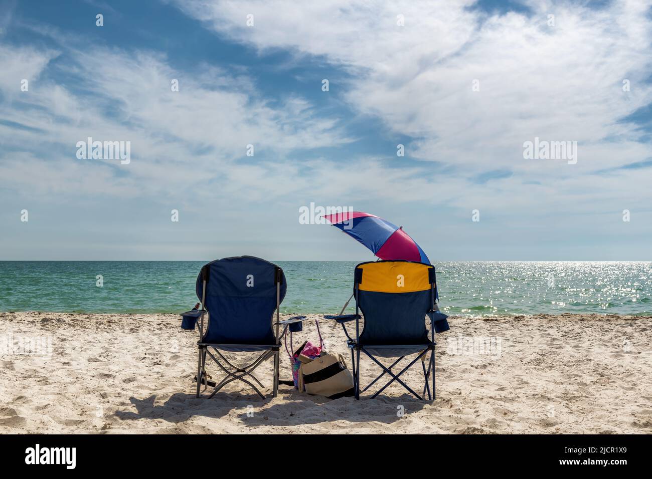 Sonnenuntergangsansicht von Liegestühlen mit Strandzubehör in Naples Beach, Florida, USA Stockfoto