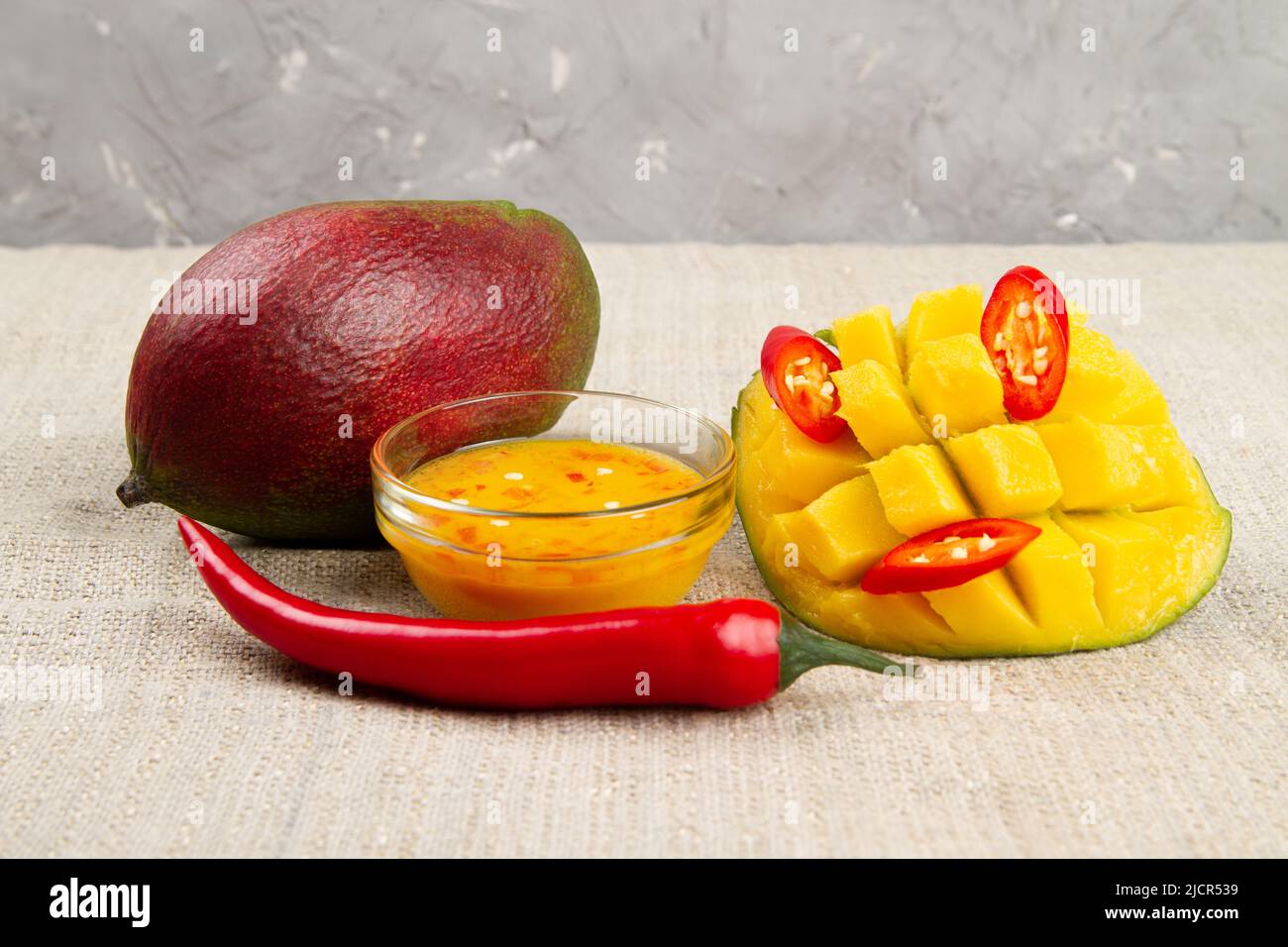 Mango-Chilisauce, Mangofrucht und Chilischote auf Jutetuch. Rustikales Stillleben Stockfoto