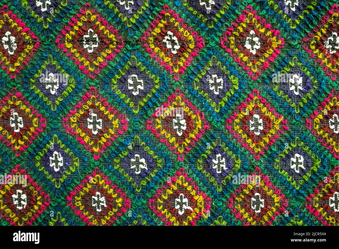 Handgefertigter mehrfarbiger Teppich mit Rautenornament, geflochtener Matte, Nahaufnahme, Texturhintergrund. Stockfoto