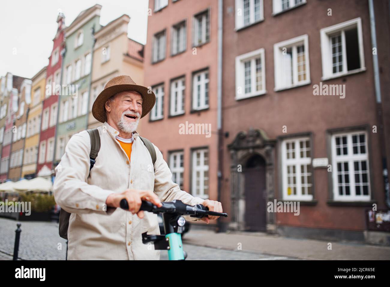 Porträt eines glücklichen älteren Mannes Tourist Reiten Roller im Freien in der Stadt Stockfoto