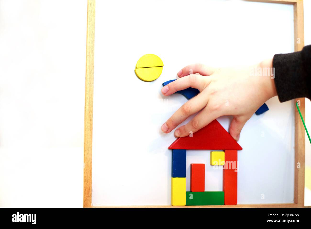 Kind spielt hölzerne magnetische Lernspiel. Mädchen spielt mit einem Spielzeug auf weißem Hintergrund. Stockfoto