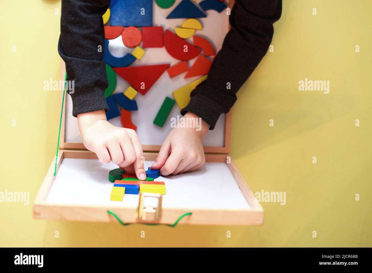 Kind spielt hölzerne magnetische pädagogische Spiele. Kinder spielen Mosaik. Blick von oben. Kind spielt mit einem Konstrukteur Stockfoto