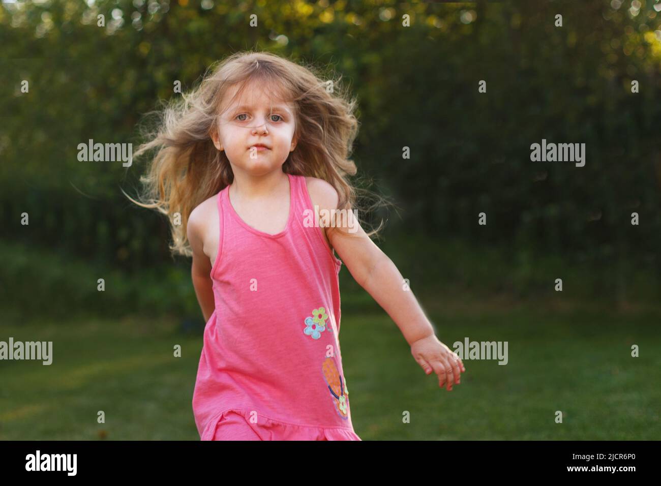 Happy Baby lächelnd. Kleines Mädchen läuft bei Sonnenuntergang im Freien Stockfoto