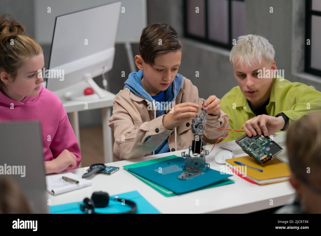 Kinder mit Lehrer arbeiten zusammen an einem Projekt mit elektrischen Spielzeugen und Robotern im Robotik-Klassenzimmer Stockfoto
