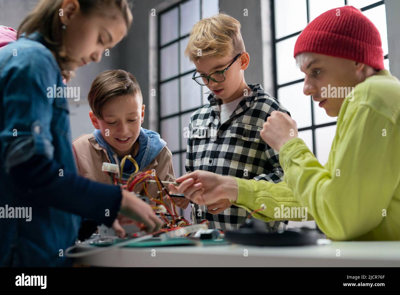 Kinder mit Lehrer arbeiten zusammen an einem Projekt mit elektrischen Spielzeugen und Robotern im Robotik-Klassenzimmer Stockfoto