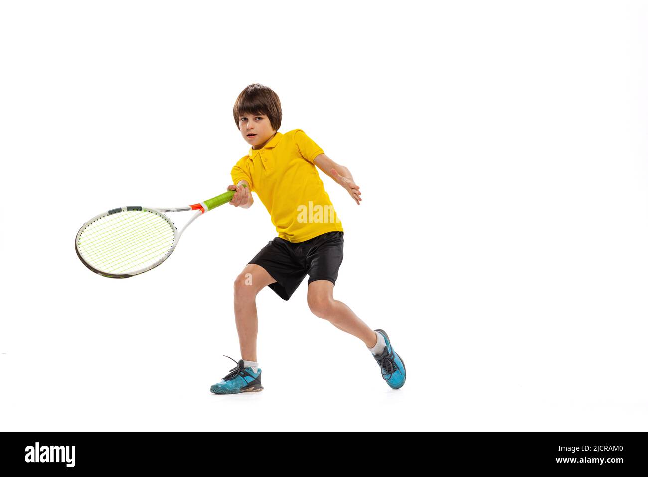 Ein sportliches Kind spielt Tennis isoliert über weißem Studiohintergrund. Konzept von Sport, Leistungen, Hobby, Können Stockfoto