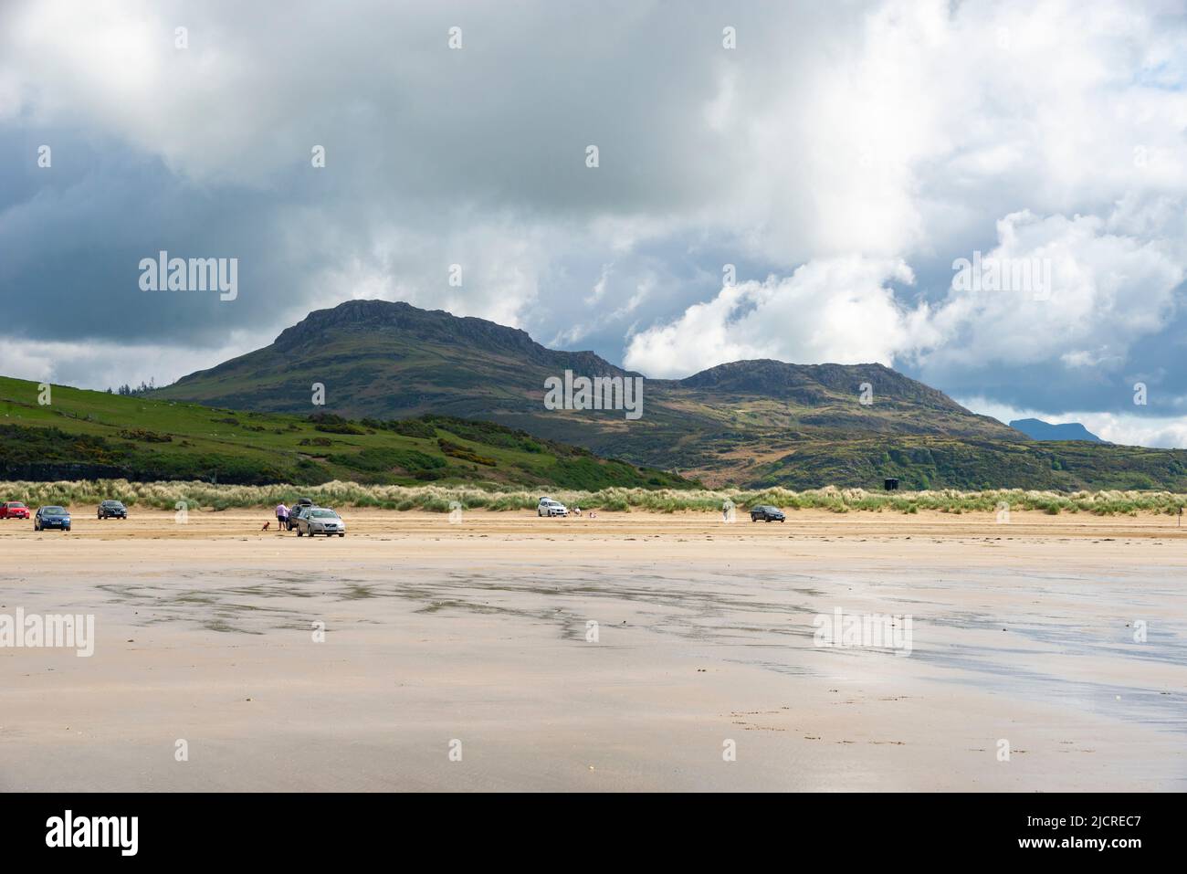 Touristen parkten am Black Rock Sands in der Nähe von Porthmadog an der Küste von Nordwales. Moel y gest im Hintergrund. Stockfoto