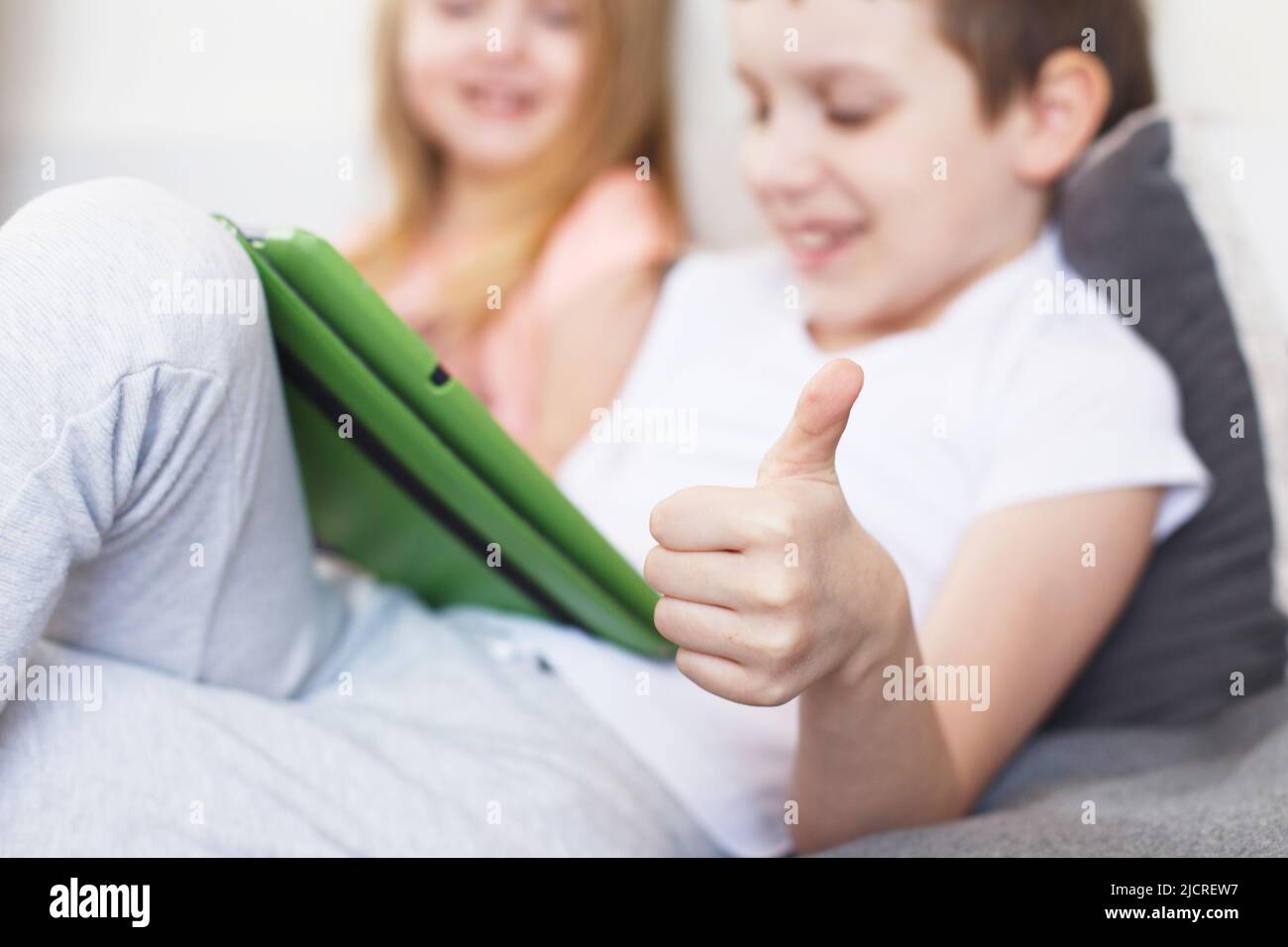Fernunterricht online Bildung. Kinder sitzen mit einem Tablet auf dem Bett im Zimmer. Kinder mit einem Gadget. Quarantäne und Selbstisolierung. Stockfoto
