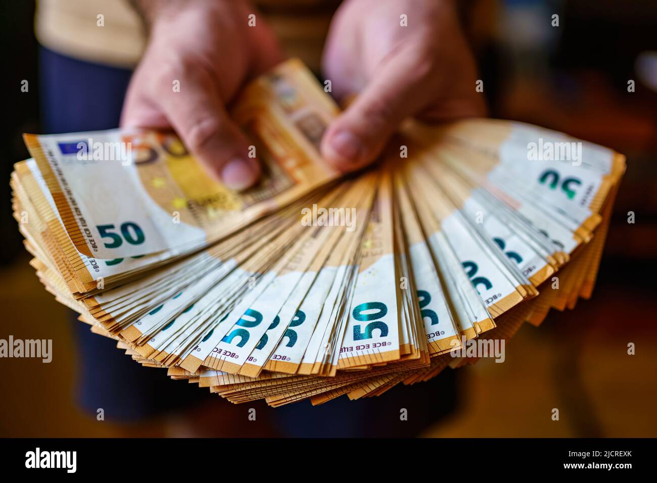 Ein Haufen von 50 Euro-Scheinen, die von einer Person in Händen gehalten werden. Stockfoto