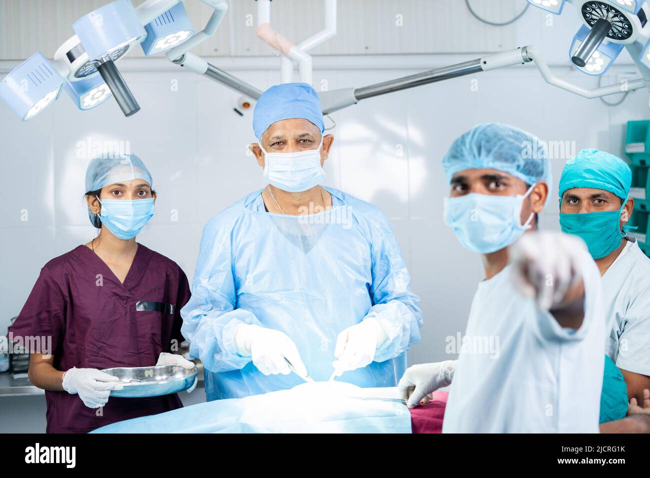 Surreon operieren oder Chirurgie, indem Sie Monitor auf OP-Theater mit unterstützenden Mitarbeitern - Konzept der Technologie, medizinische Fachkräfte und Stockfoto