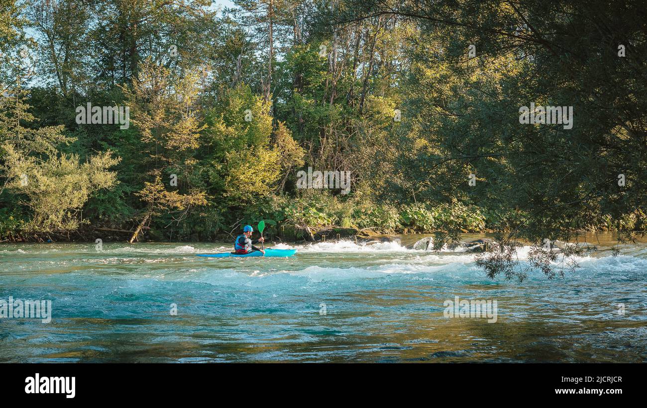 Kaukasischer Mann, der stromaufwärts auf den Wildwasserkrapiden Kajak fahren und hart auf dem turbulenten Fluss paddeln kann Stockfoto