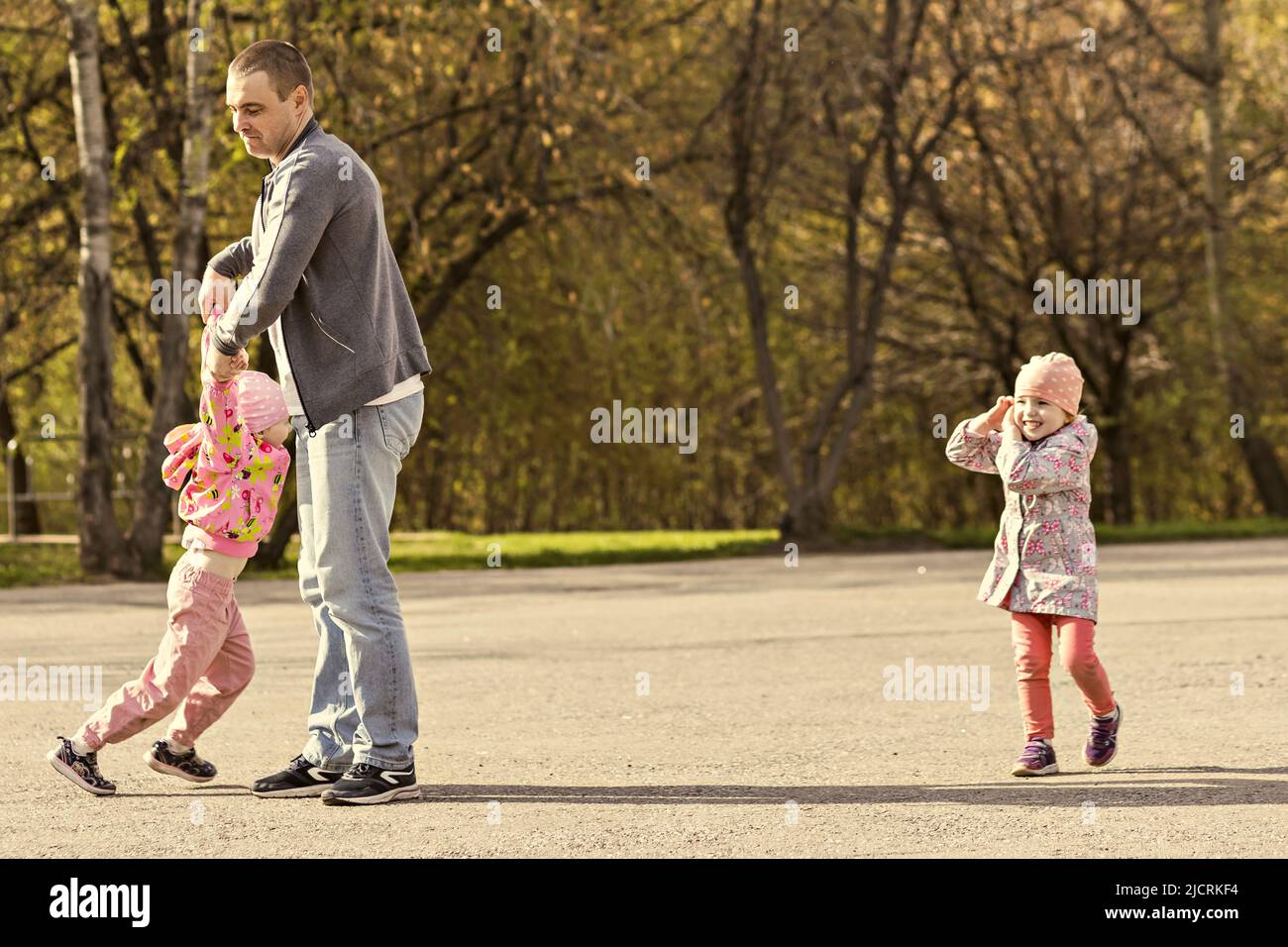 Papa spielt mit seinen Töchtern im Park. Ein Mädchen herumwirbeln. Familie. Stockfoto