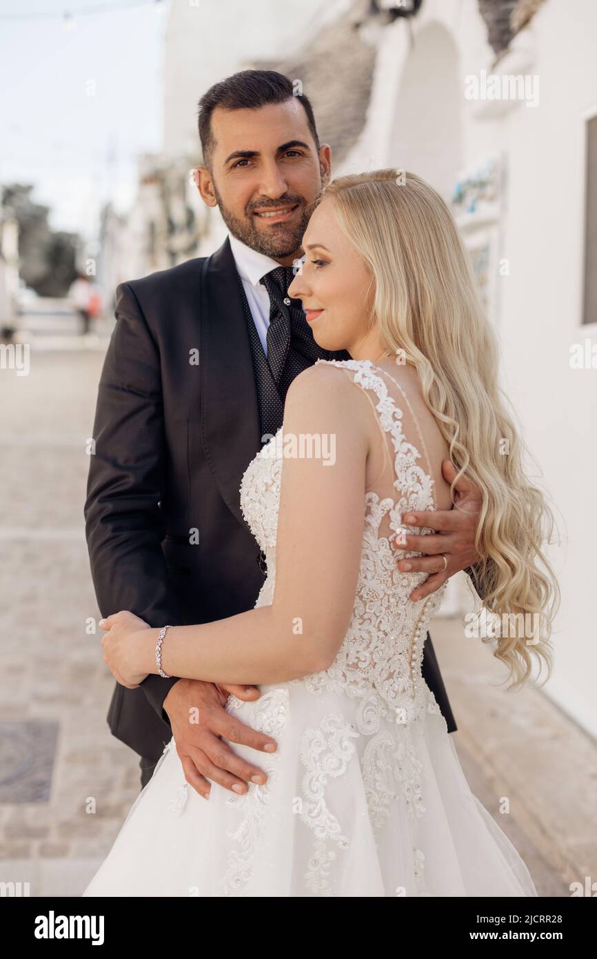 Gerade verheiratetes Paar, hübsche lockige blonde Frau, Braut und dunkelhaariger bärtiger Mann, Bräutigam, der zusammen steht. Frisch Vermählt Stockfoto