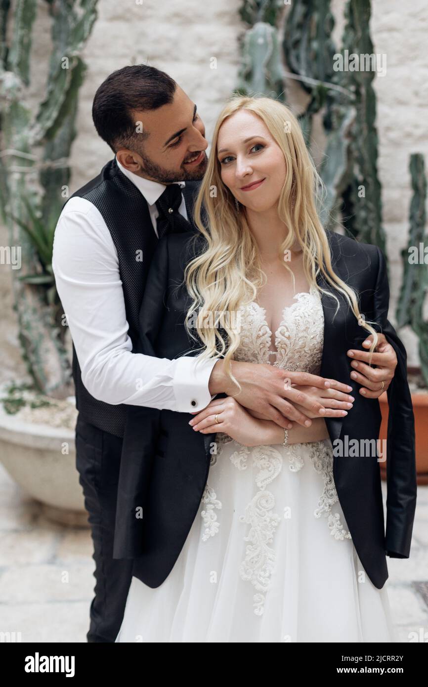 Vertikales Porträt eines fröhlichen romantischen Ehepaares, einer blonden Frau und eines schwarzhaarigen Mannes. Sich gegenseitig pflegen Stockfoto