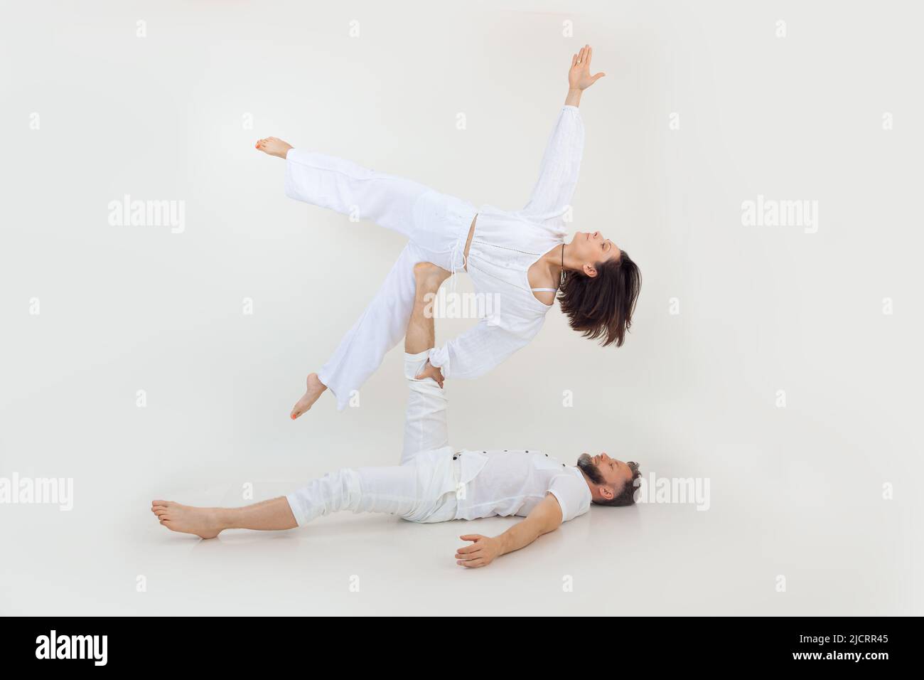 Mann und Frau, Familie bei Sportübungen, Fitness und Yoga. Gesunder Lebensstil. Männchen hält Weibchen an den Beinen, üben Stockfoto