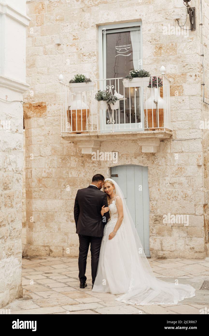 Vertikales Porträt von frohen, fröhlichen romantischen Ehepaar, Hochzeit. Überkleidet, umarmt in der historischen Stadt Italien Stockfoto
