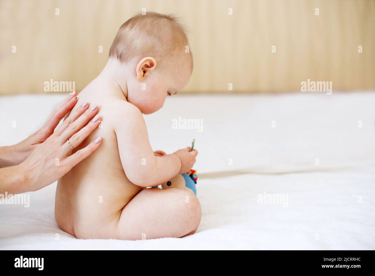 Mutter und Baby. Muts Liebe und Zärtlichkeit. Mutter massiert Baby im Bett zu Hause Stockfoto