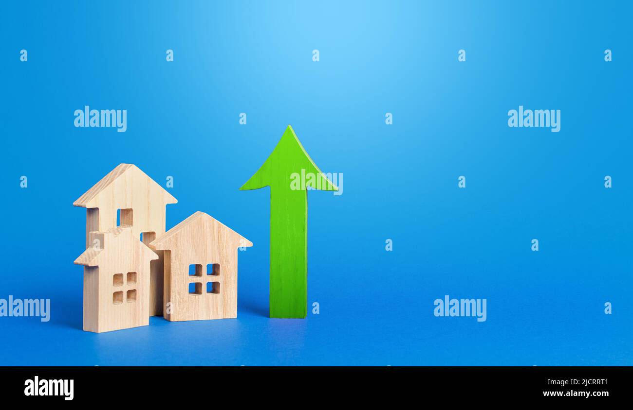 Häuser und grüner Pfeil nach oben. Steigende Preise und Mieten. Verdienen Sie Geld, indem Sie in Immobilien investieren. Verbesserung des Wohnbaus Hohe Nachfrage. Anstieg der Hypothekenzinsen. Zoll Stockfoto