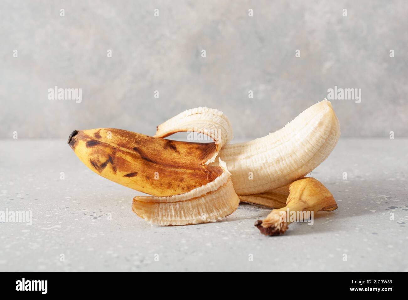 Reife überreife Bio-Bananen auf konkretem Hintergrund. Hässliche Lebensmittel Null Abfall Konzept Stockfoto