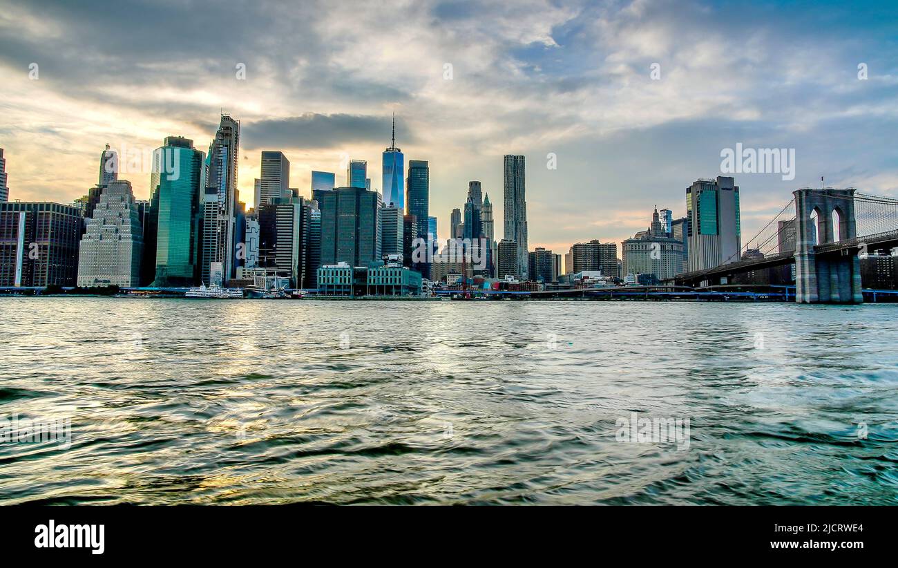 NEW YORK, NY, USA - 13. JUNI 2022: Wunderschöne Aussicht über den East River mit Manhattan in der Nähe der Brooklyn Bridge bei Sonnenuntergang Stockfoto