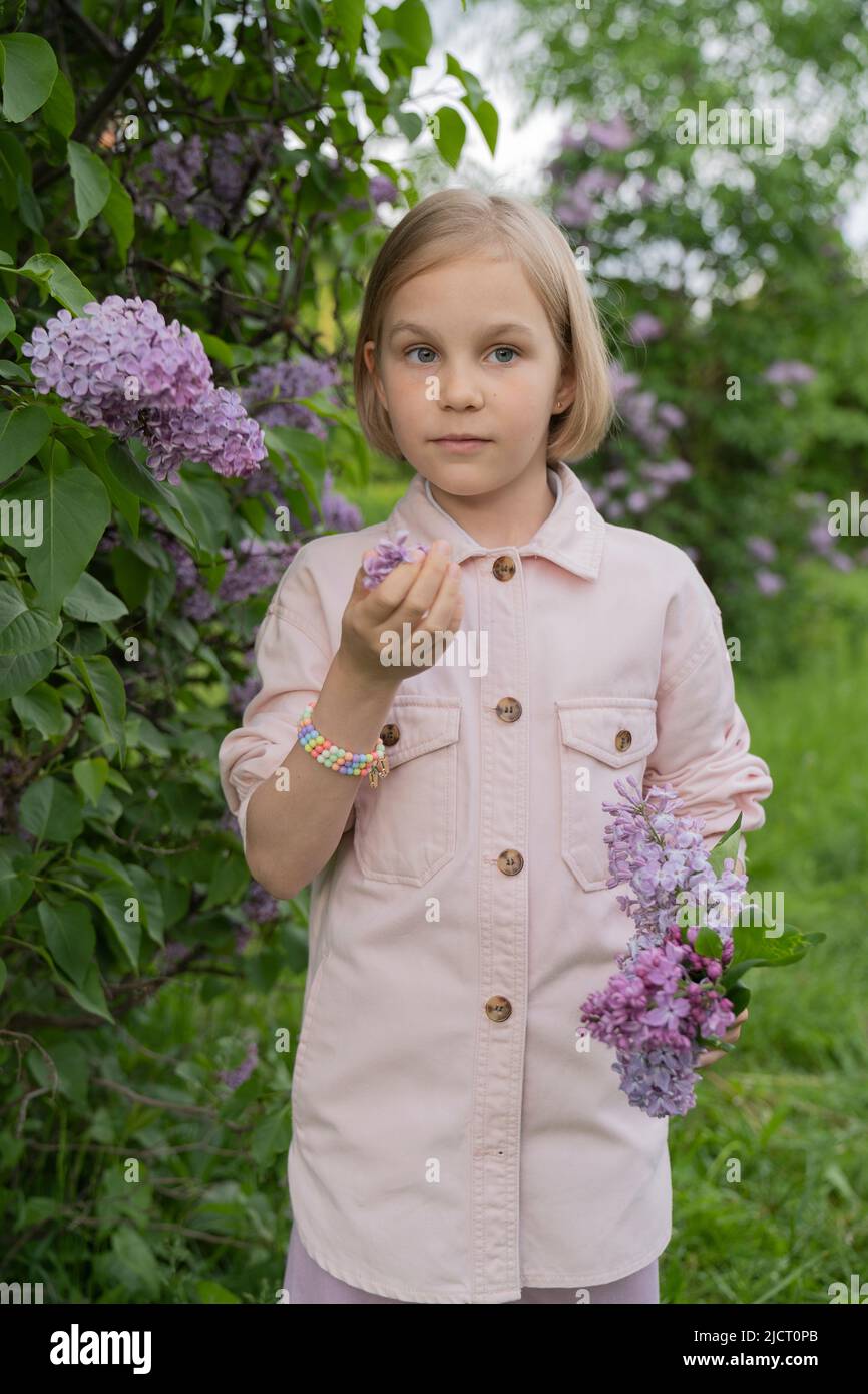 Porträt eines 8-jährigen Mädchens in einem Park mit Fliedern. Stockfoto