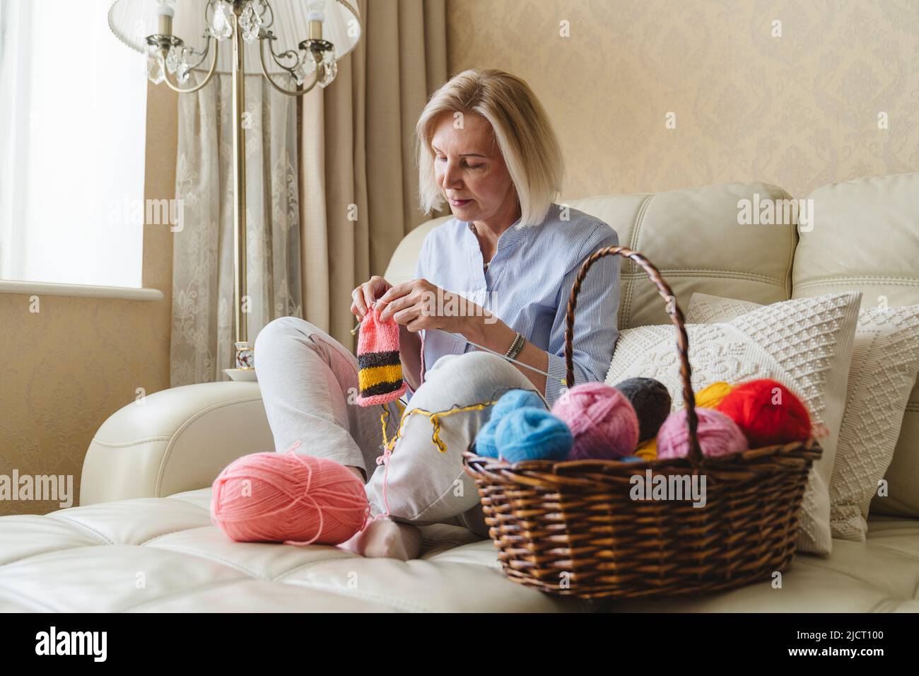 Eine Frau strickt mit ihren eigenen Händen Nadeln aus Wollgarn. Stockfoto