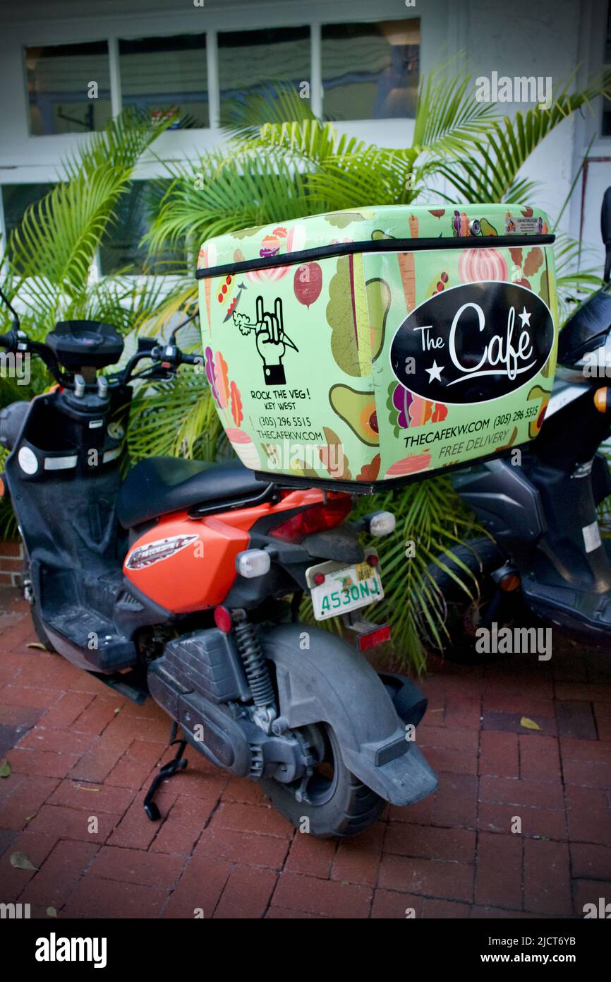 Der Cafe Delivery Scooter parkte und wartete darauf, ein Essen zum Mitnehmen aus diesem meist vegetarischen Restaurant in der Altstadt von Key West, Florida, zu liefern Stockfoto