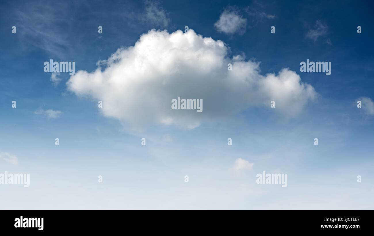 Blauer Himmel und kleine flauschige einzelne Wolke, die vom Tageslicht erleuchtet wird. Natur Hintergrund Stockfoto