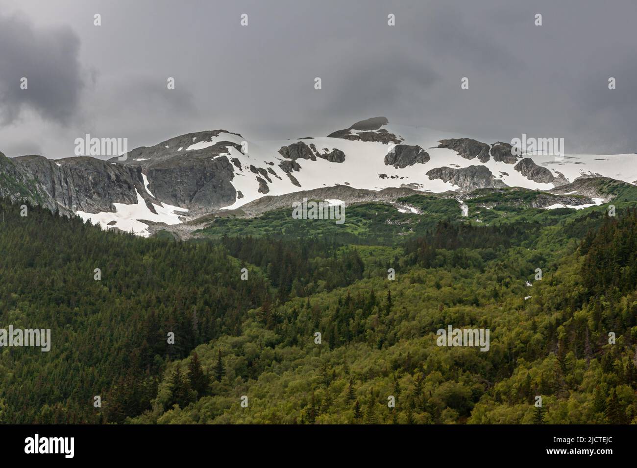 Skagway, Alaska, USA - 20. Juli 2011: Taiya Inlet über Chilkoot Inlet. Landschaft mit dunkelgrauer Wolkenlandschaft über der Bergkette mit Schneeflecken Stockfoto