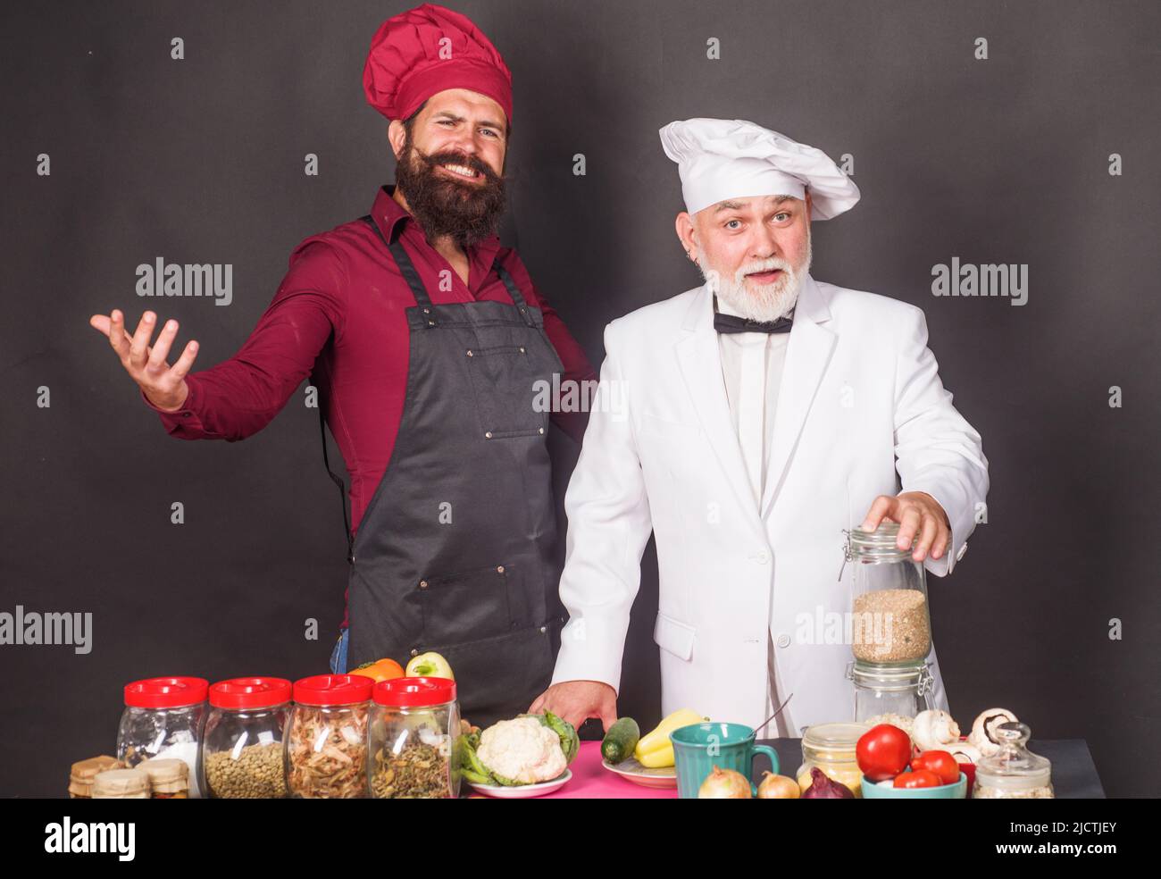 Zwei professionelle Köche in Kochuniform und Schürze in der Restaurantküche. Kochen. Leckeres Essen. Stockfoto