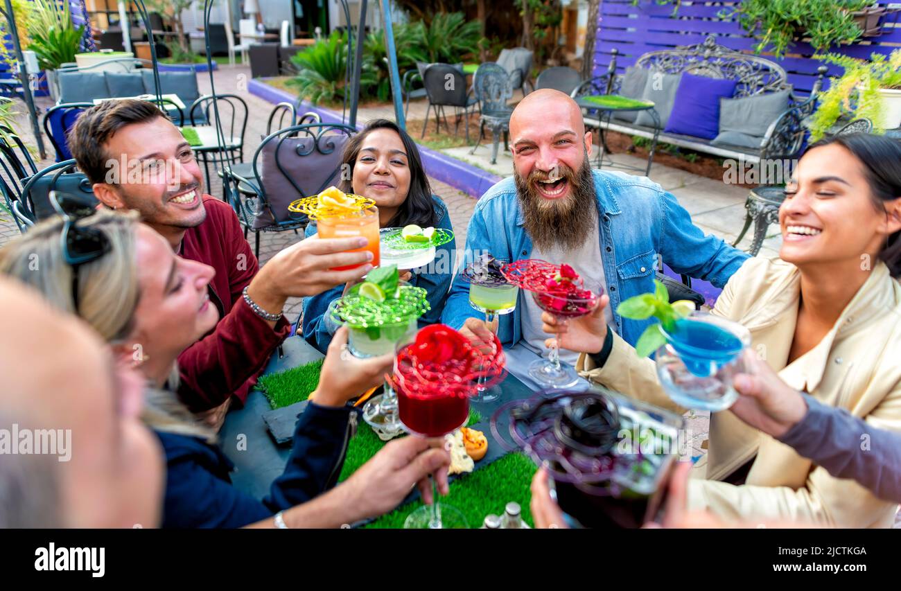 Fröhliche, vielfältige, große Gruppe multikultureller Freunde, die mit wunderschönen Gourmet-Cocktailgläsern im Barrestaurant feiern Stockfoto