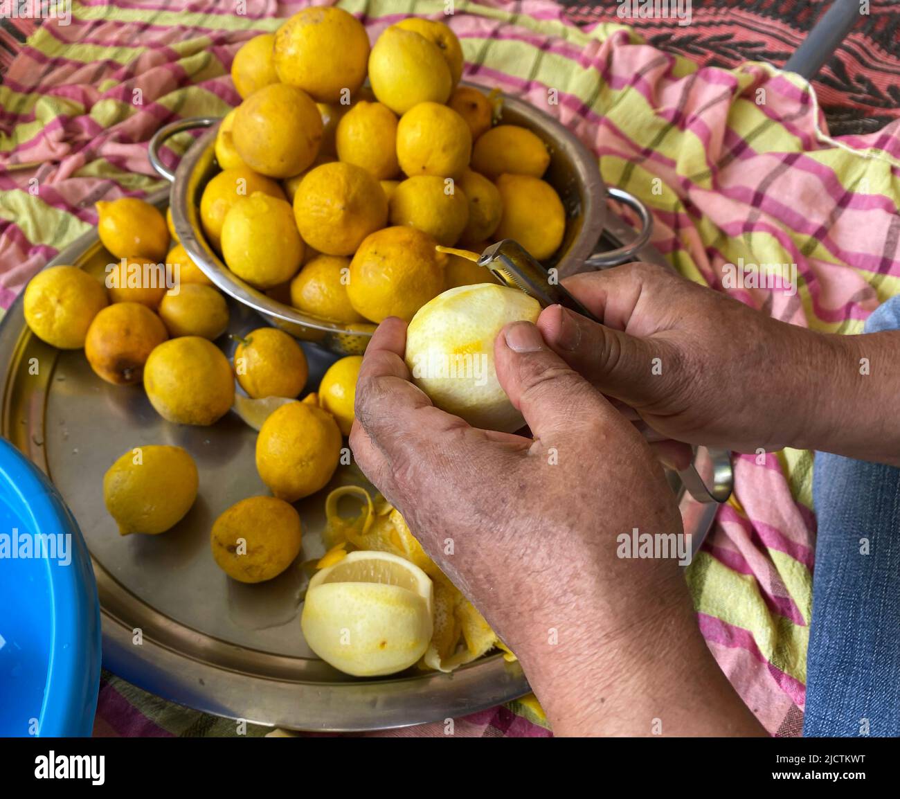 Mann schält Zitrone mit Schäler. Vorbereitung der traditionellen hausgemachten Limonade. Selektiver Fokus auf die Hände Stockfoto