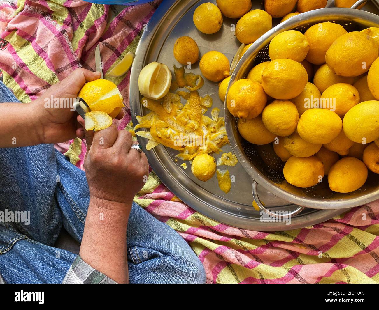 Mann schält Zitrone mit Schäler. Vorbereitung der traditionellen hausgemachten Limonade. Selektiver Fokus auf die Hände Stockfoto