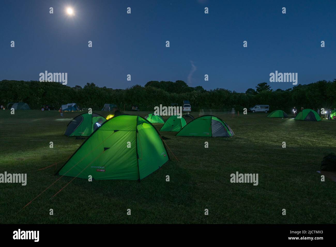 Eine Gruppe von Zelten (auf einer Reise des Duke of Edinburgh) auf einem Feld unter einem fast Vollmond in Dorset, Großbritannien. Stockfoto