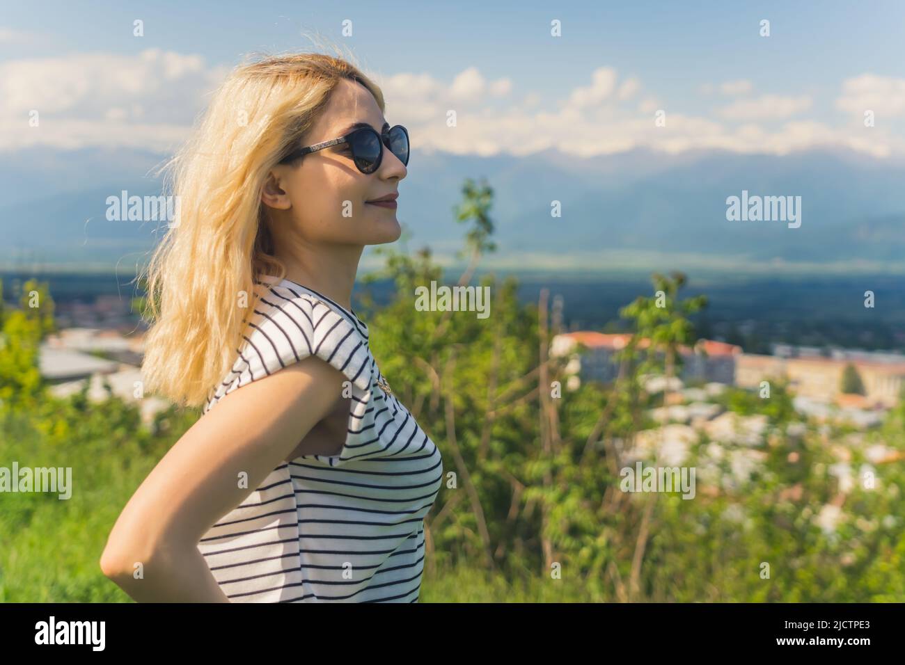 Profilaufnahme eines blonden kaukasischen Mädchens, das mit einem schönen Blick auf die Berge genießt und weit weg schaut. Mittlere Nahaufnahme im Freien. Hochwertige Fotos Stockfoto