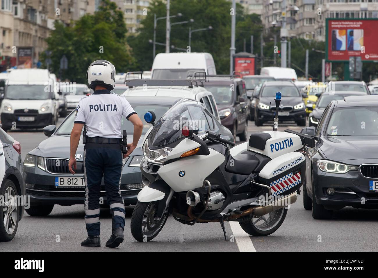 Bukarest, Rumänien - 15. Juni 2022: Ein Polizist lenkt Autos im Verkehr ab, um einen gesperrten Teil der Straße aufgrund einer Gewerkschaftskundgebung auf dem Siegesplatz zu umgehen. Stockfoto