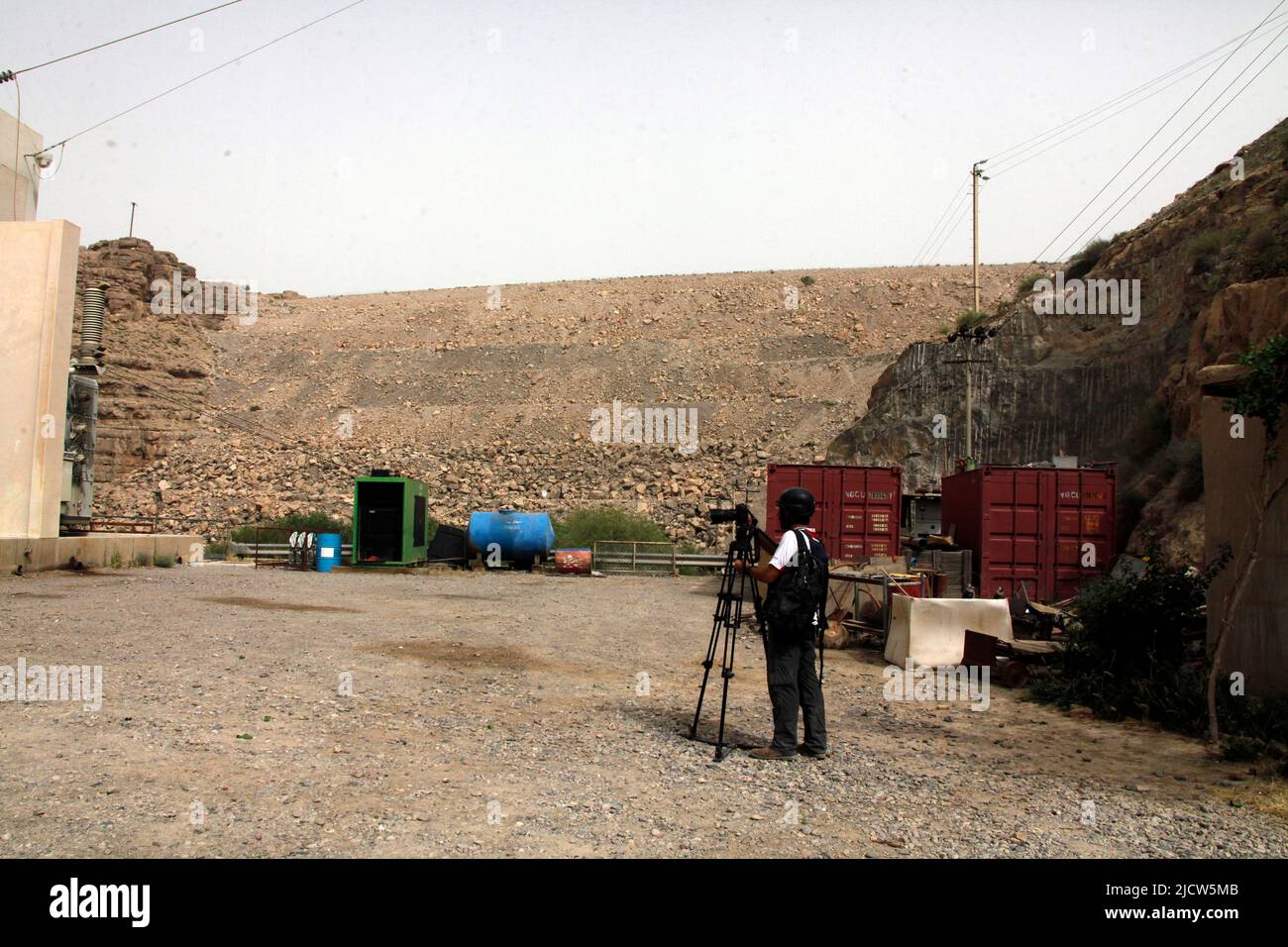 Ben Foley, Kameramann, mit Al Jazeera English News Channel filmt die Außenseite des Kajaki-Staudamms mit dem Damm direkt rechts von ihm Stockfoto