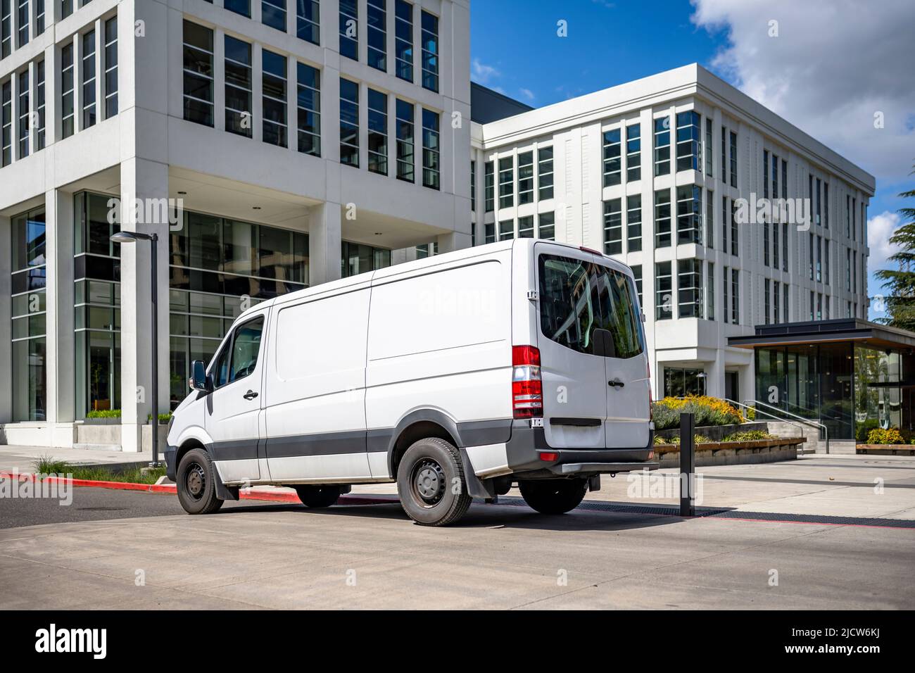 Kommerzielle weiße kompakte Ladung Mini-Van für lokale Lieferung und kleine Unternehmen stehen auf der städtischen Straße mit mehrstufigen Wohnwohnung Stockfoto