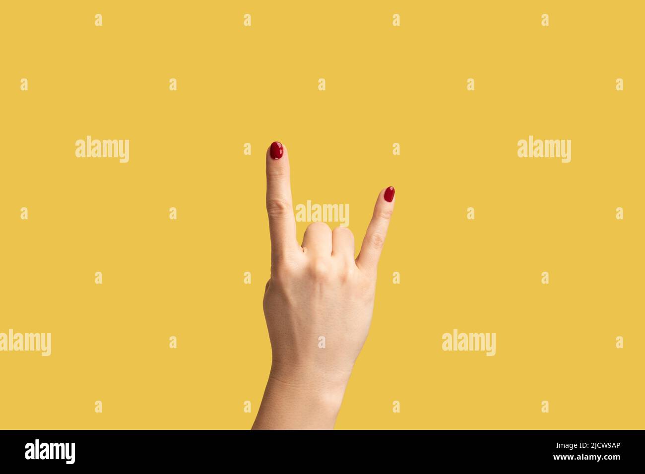Nahaufnahme Frau Hand zeigt Rock Zeichen, Rock and Roll Zeichen Hand Geste. Innenaufnahme des Studios isoliert auf gelbem Hintergrund. Stockfoto