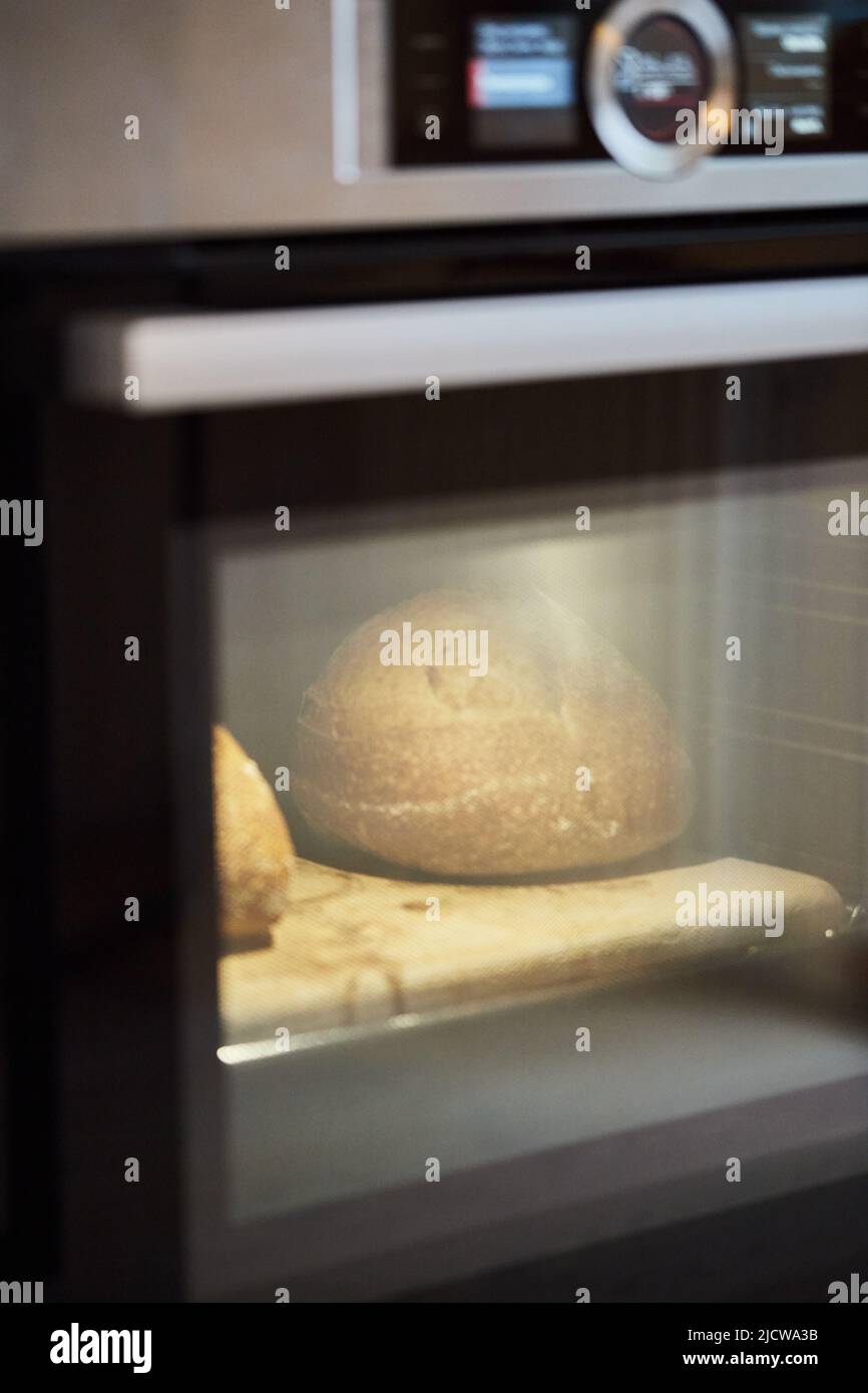 Der Prozess der Herstellung von Weizenbrot zu Hause. Brot im Ofen backen. Das Konzept der gesunden hausgemachten Speisen. Vertikales Foto. Stockfoto