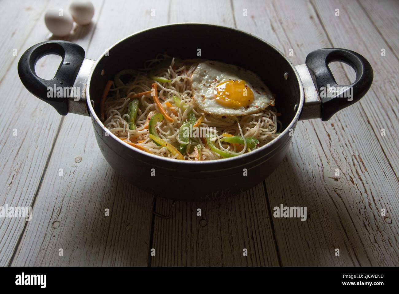 Gebratene Nudeln in einer Pfanne auf einem Hintergrund anbraten. Nahaufnahme, selektiver Fokus. Stockfoto