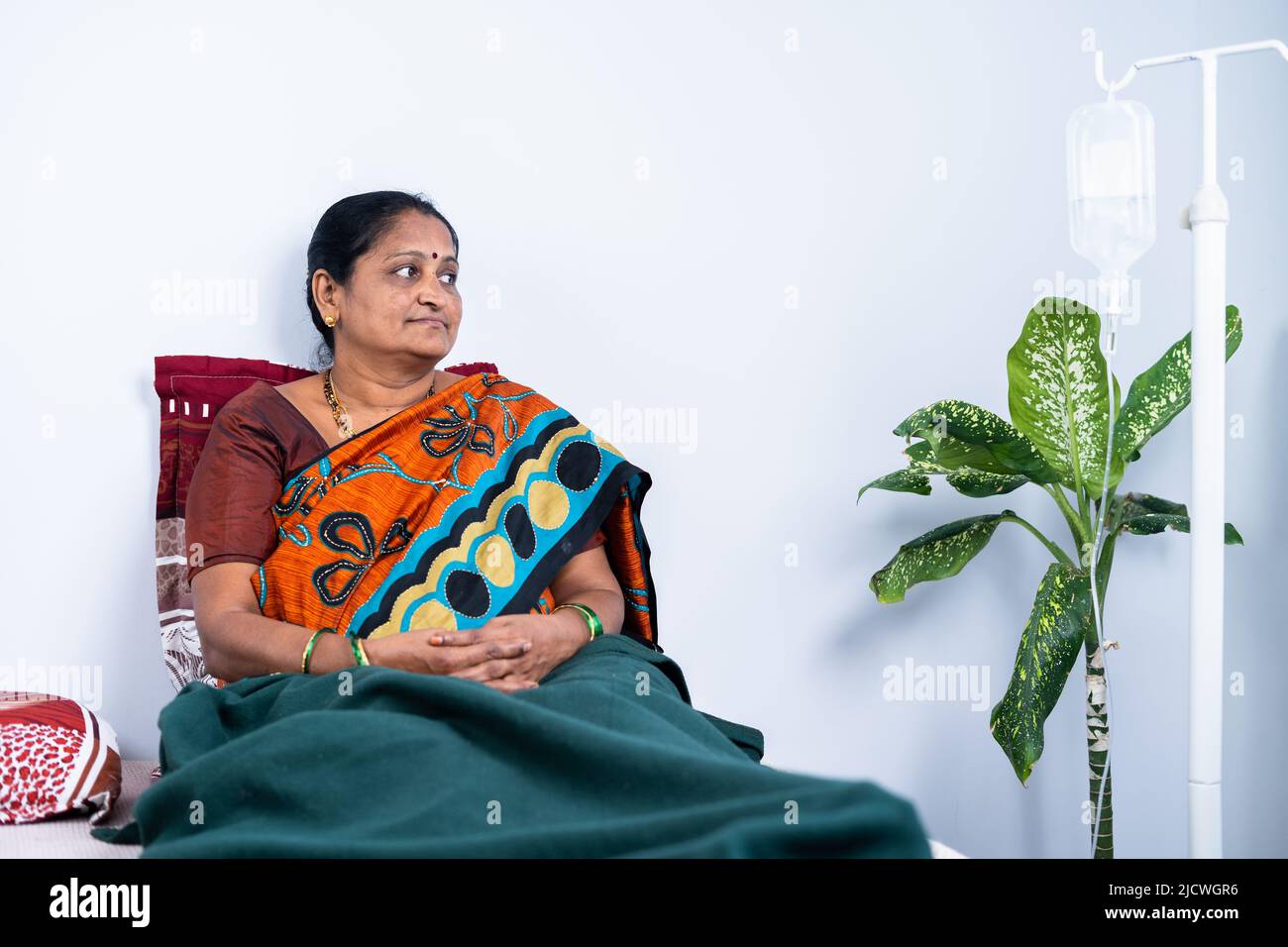 Tief denkende, kranke Frau mittleren Alters auf dem Bett zu Hause - Konzept der Gesundheitsversorgung und medizinischen Fragen, psychische Erkrankungen und Einsamkeit Stockfoto