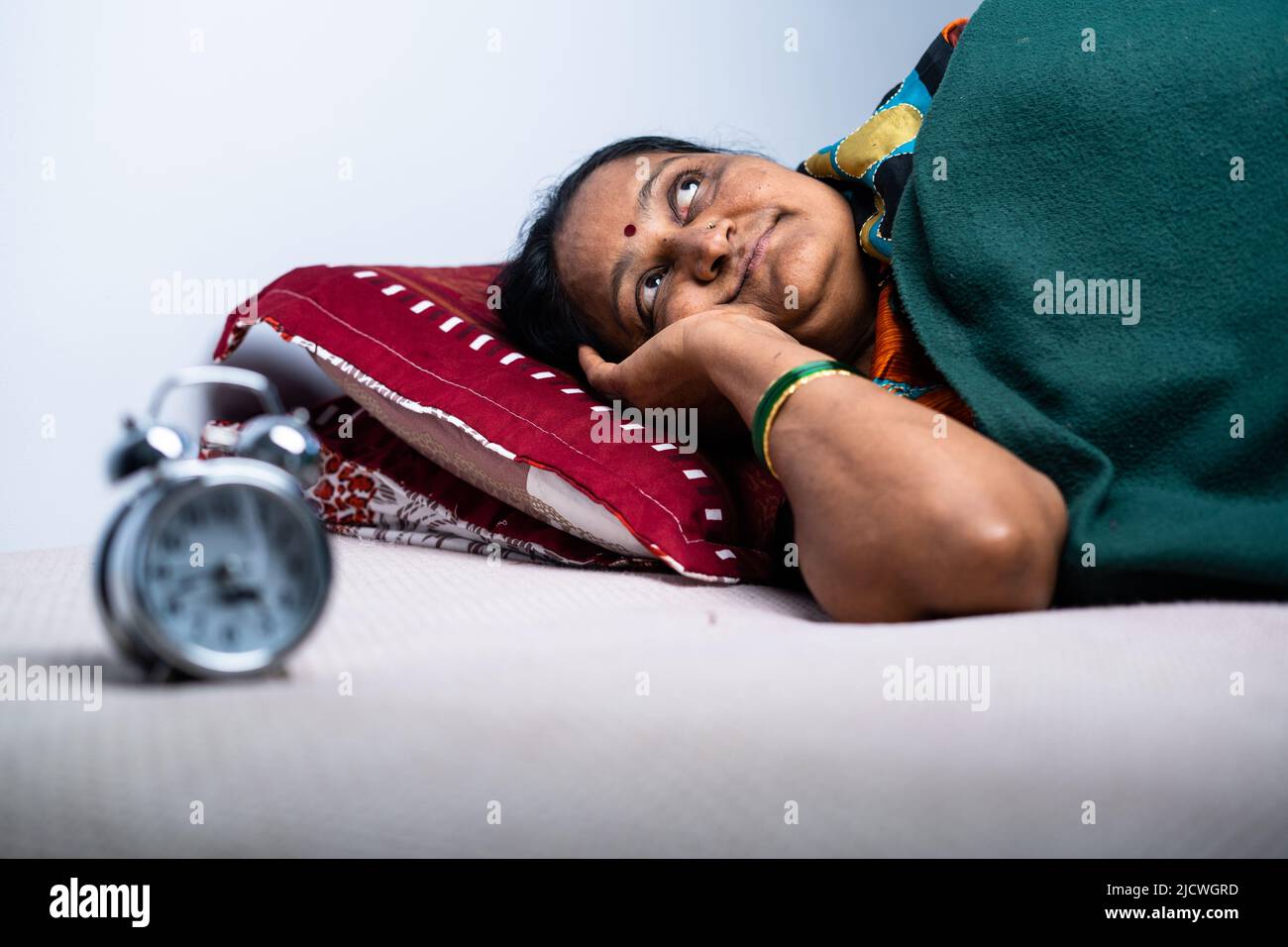 Eine Frau im Alter zwischen zwei Jahren, die nachts im Schlafzimmer an Schlaflosigkeit leidet - ein Konzept von Alptraum, Schlaflosigkeit und Traurigkeit. Stockfoto