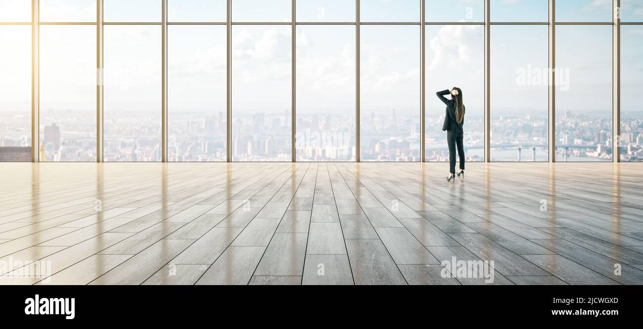 Gedanken über die Zukunft und Karrieremöglichkeiten Konzept mit nachdenklichen Geschäftsfrau Blick auf die Skyline der Stadt durch großes Fenster in leeren geräumigen Halle wi Stockfoto