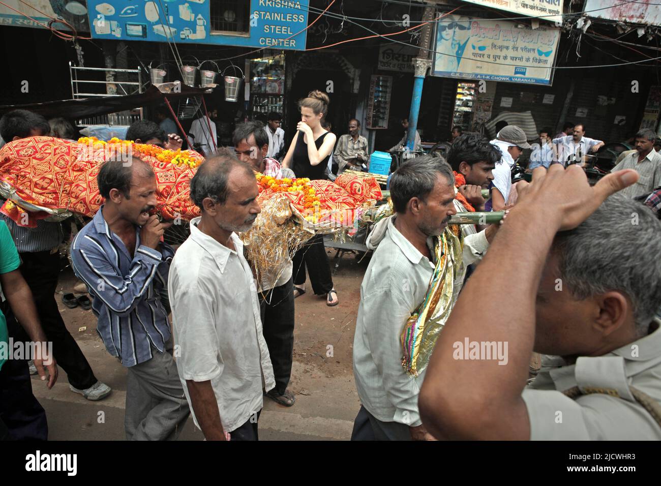 Männer, die einen Leichnam tragen, gehen auf einer verkehrsreichen Straße zu einem der Kremierungsghats am Ufer des Flusses Ganges, um dort in Varanasi, Uttar Pradesh, Indien, eine Leichenverbrennung zu feiern. Stockfoto